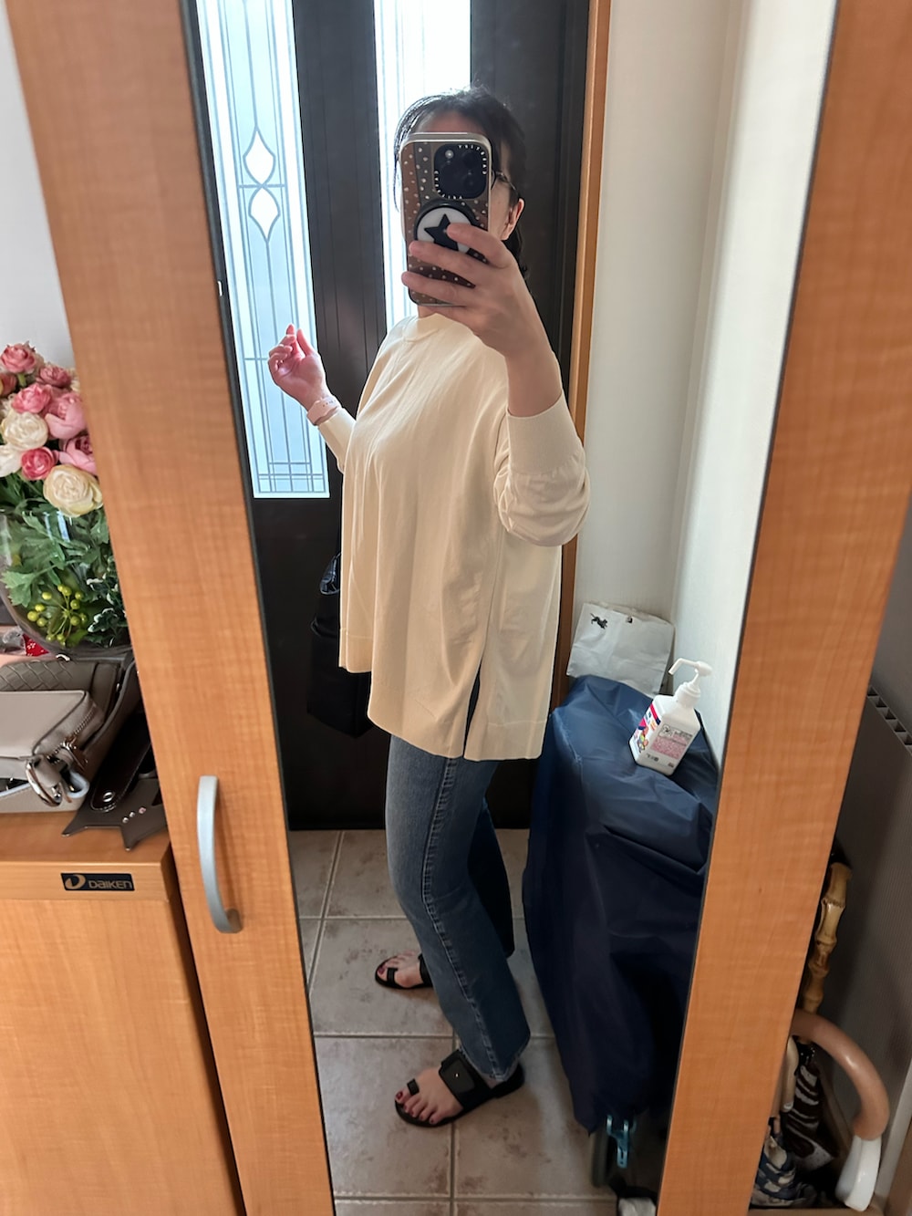 ベージュ系のニット/セーター、ブルー系のデニムパンツ、ブラック系のサンダルを着用したレディースの春コーディネートの2枚目の写真