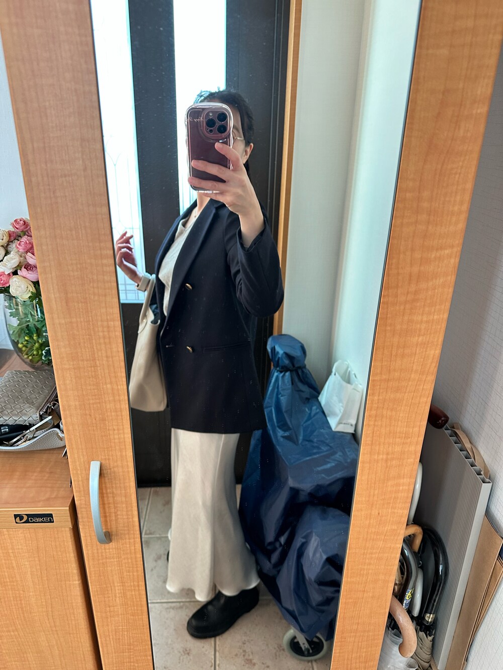 ブルー系のテーラードジャケット、ベージュ系のトートバッグ、ホワイト系のスカートを着用したレディースの秋コーディネートの2枚目の写真