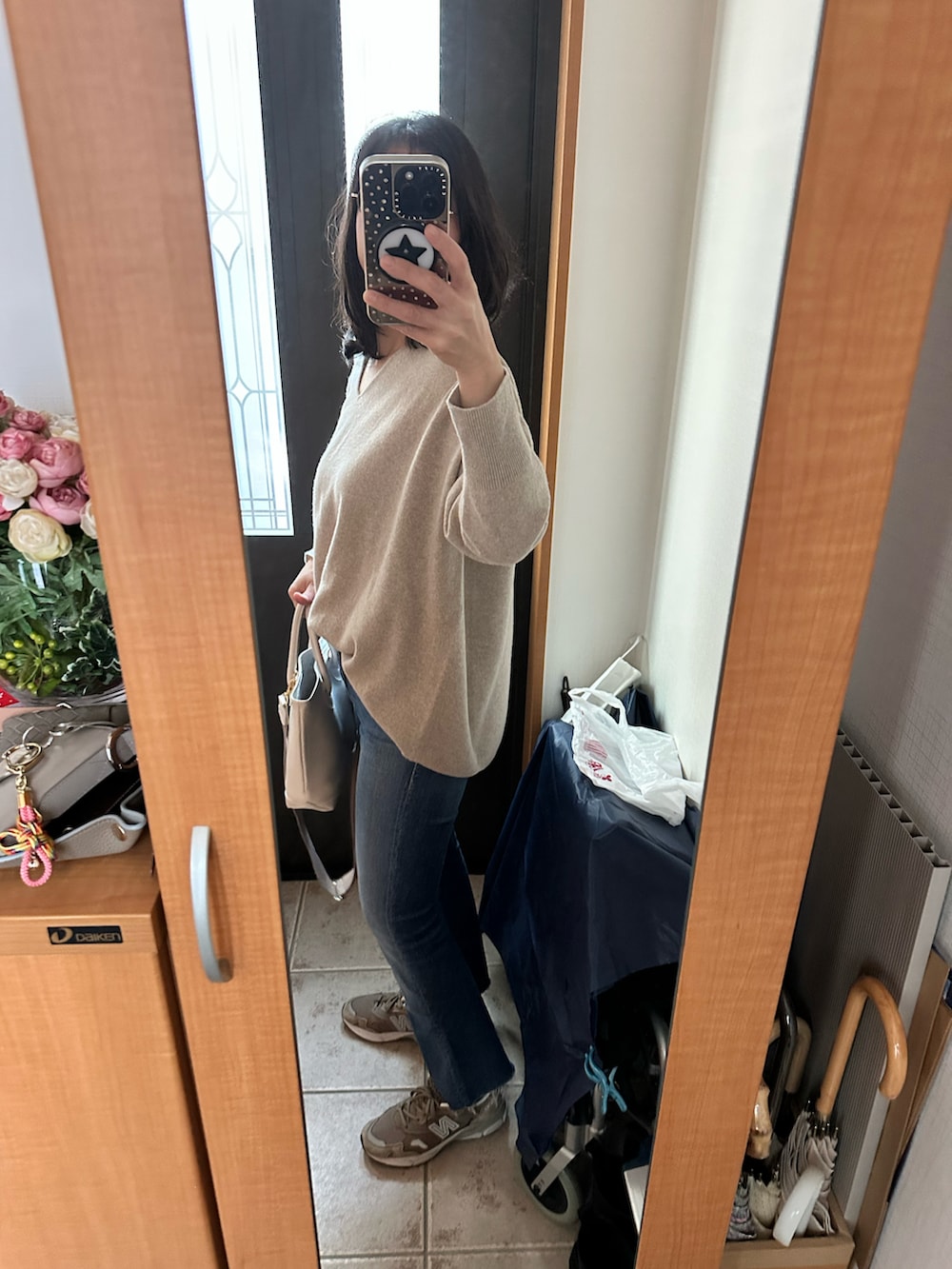 ホワイト系のバッグ、ベージュ系のニット/セーター、ブルー系のデニムパンツを着用したレディースの冬コーディネートの2枚目の写真