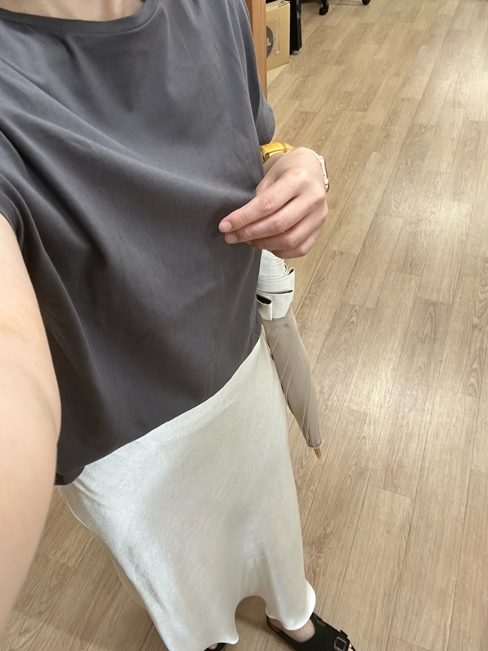 グレー系のTシャツ/カットソー、ホワイト系のスカート、ブラック系のサンダルを着用したレディースの秋コーディネートの3枚目の写真