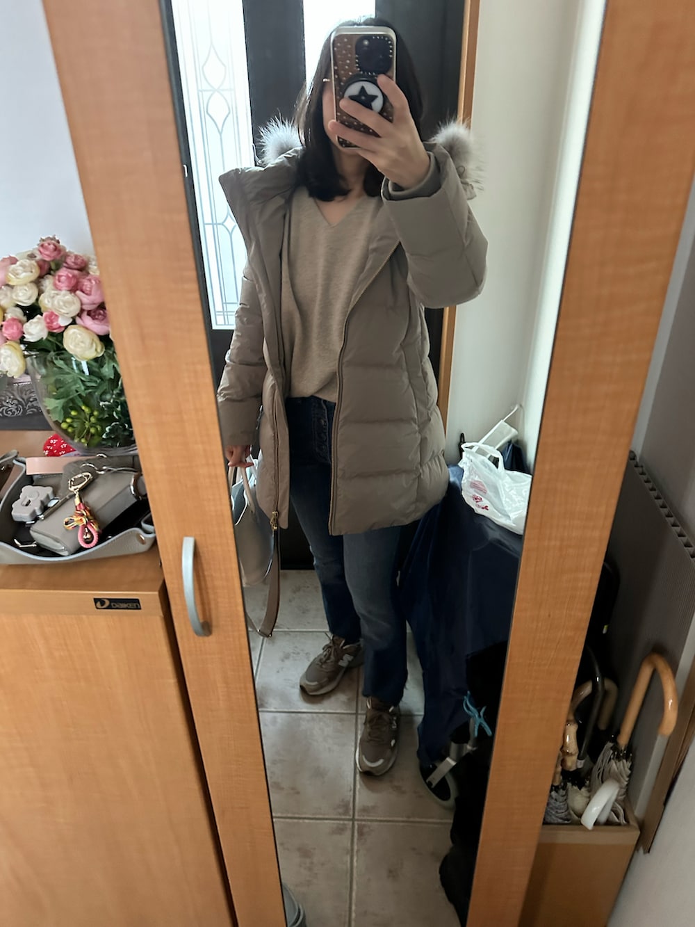 ホワイト系のバッグ、ベージュ系のニット/セーター、ブルー系のデニムパンツを着用したレディースの冬コーディネートの3枚目の写真