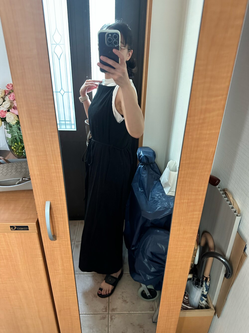 ブラック系のワンピース、ブラック系のサンダル、ホワイト系のTシャツ/カットソーを着用したレディースの夏コーディネートの2枚目の写真