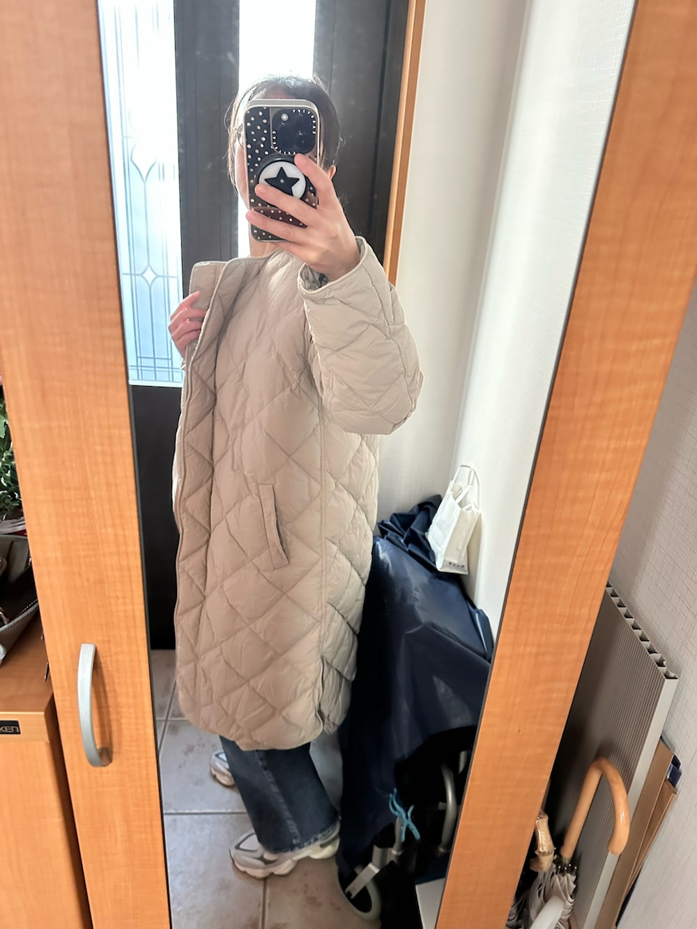 ベージュ系のダウンジャケット/コート、ベージュ系のニット/セーター、グレー系のスニーカーを着用したレディースの冬コーディネートの2枚目の写真