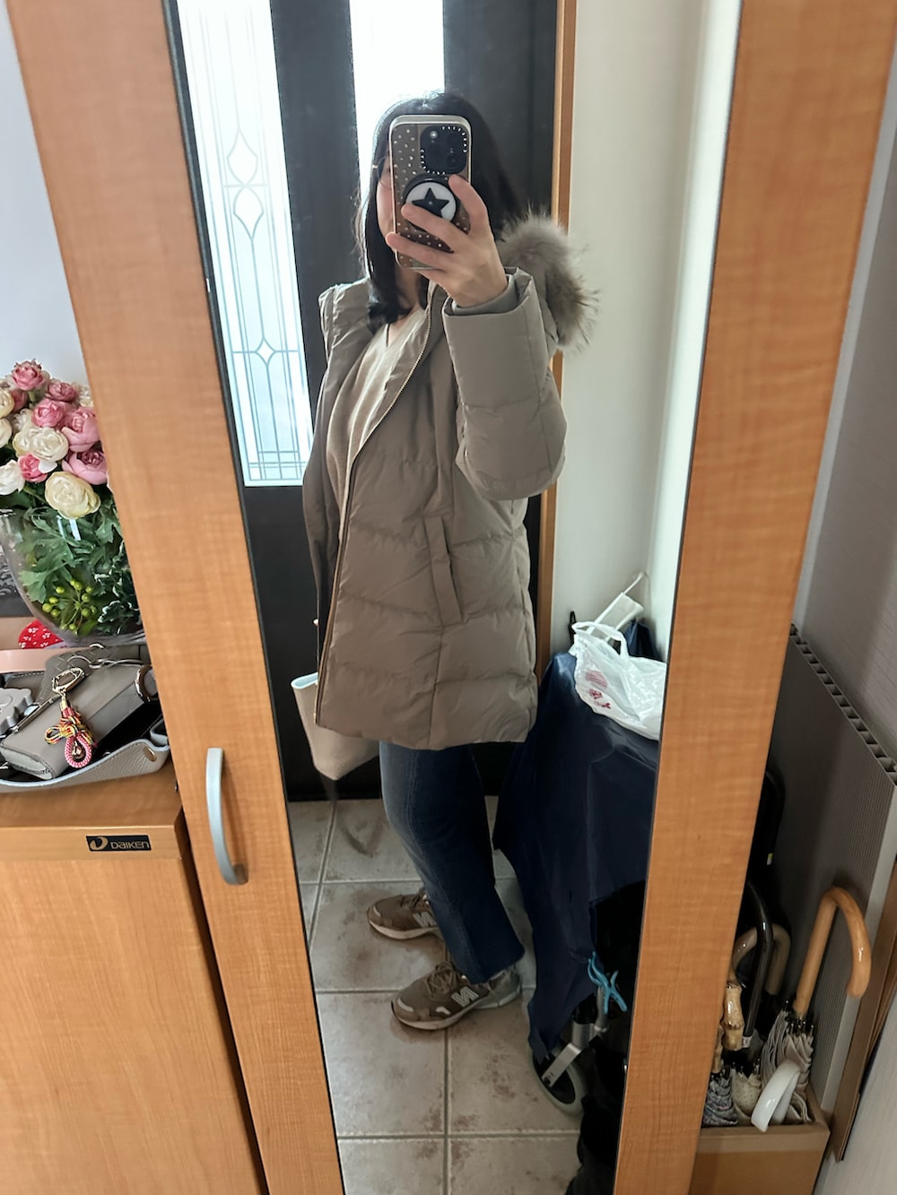 ホワイト系のバッグ、ベージュ系のニット/セーター、ブルー系のデニムパンツを着用したレディースの冬コーディネートの4枚目の写真