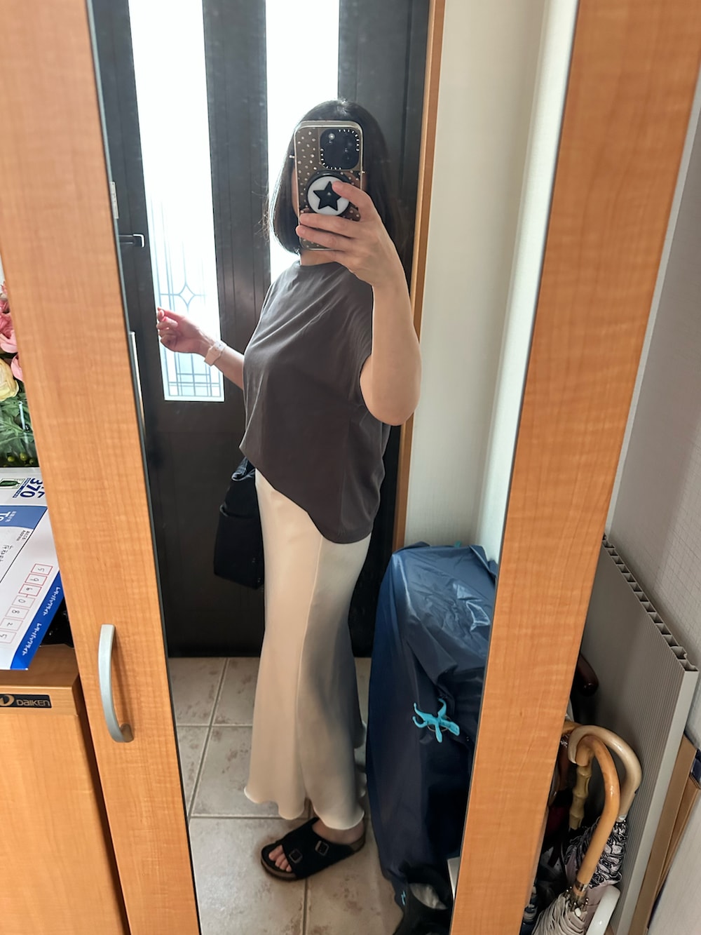 グレー系のTシャツ/カットソー、ホワイト系のスカート、ブラック系のサンダルを着用したレディースの秋コーディネートの2枚目の写真