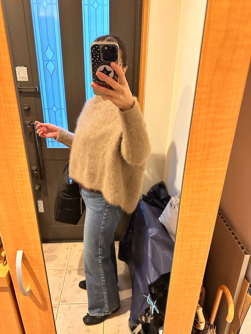 ブラウン系のニット/セーター、ブラック系のトートバッグ、ブルー系のデニムパンツを着用したレディースの冬コーディネートの2枚目の写真