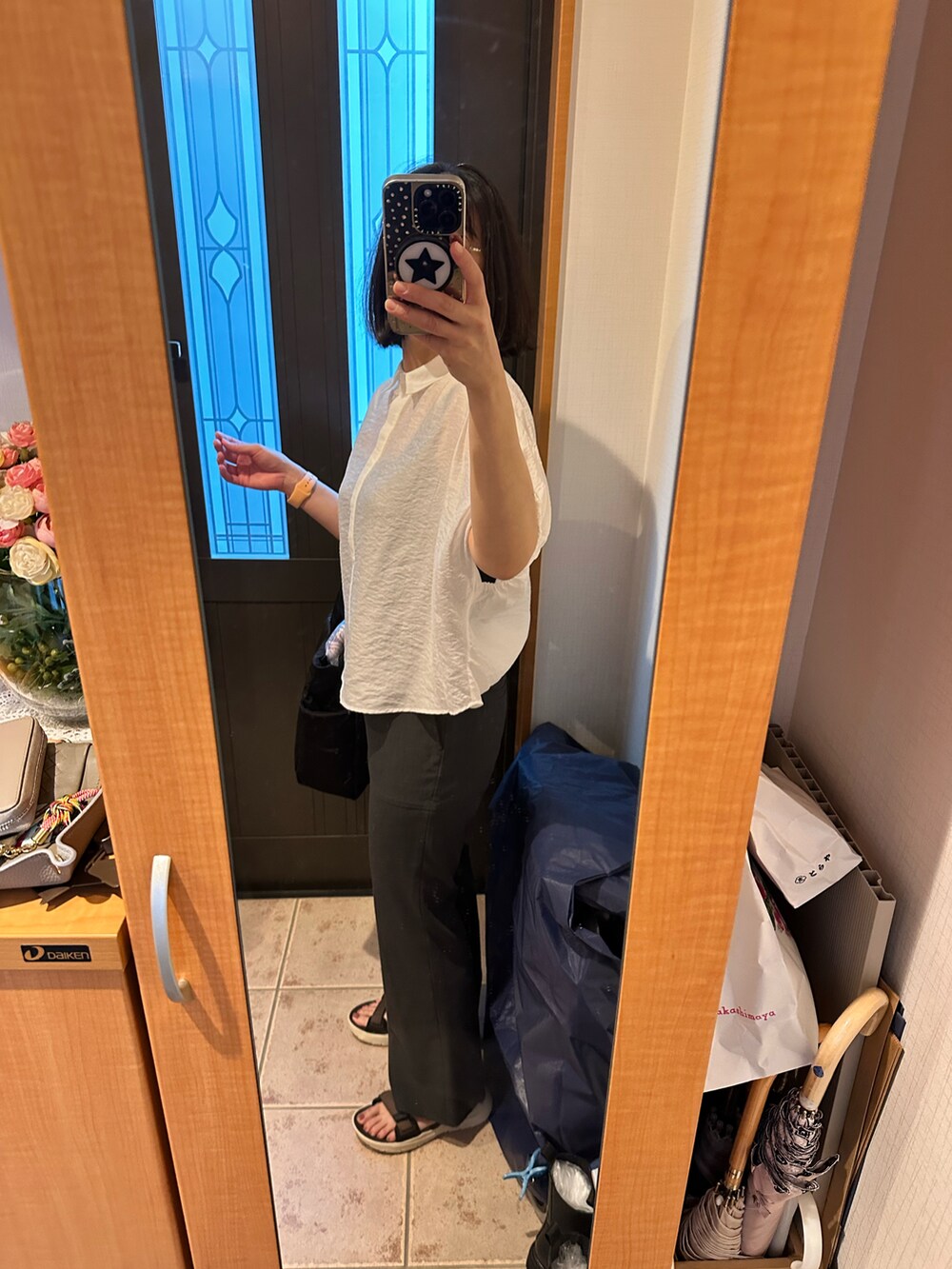 ホワイト系のシャツ/ブラウス、グレー系のスラックス、ブラウン系のサンダルを着用したレディースの夏コーディネートの2枚目の写真