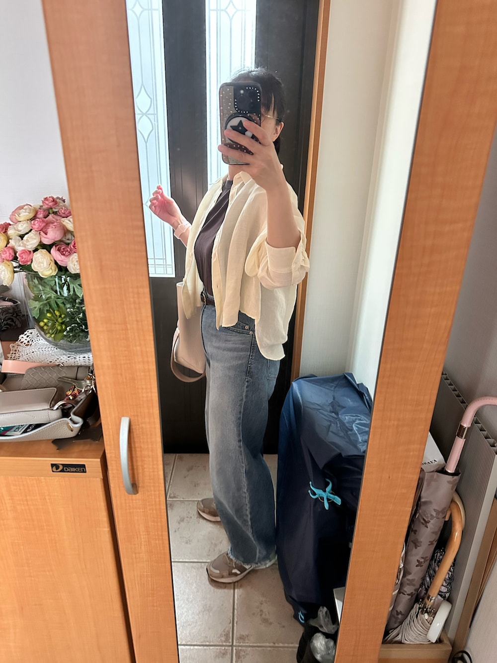 ブラウン系のタンクトップ、ベージュ系のシャツ/ブラウス、ブルー系のデニムパンツを着用したレディースの秋コーディネートの2枚目の写真