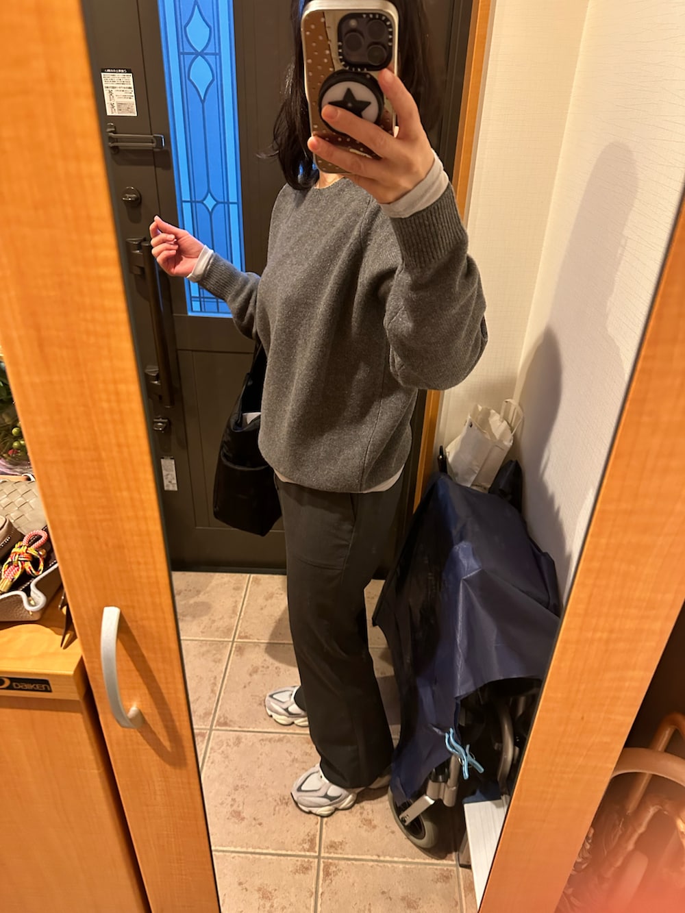 グレー系のスラックス、ブラック系のトートバッグ、グレー系のニット/セーターを着用したレディースの冬コーディネートの2枚目の写真