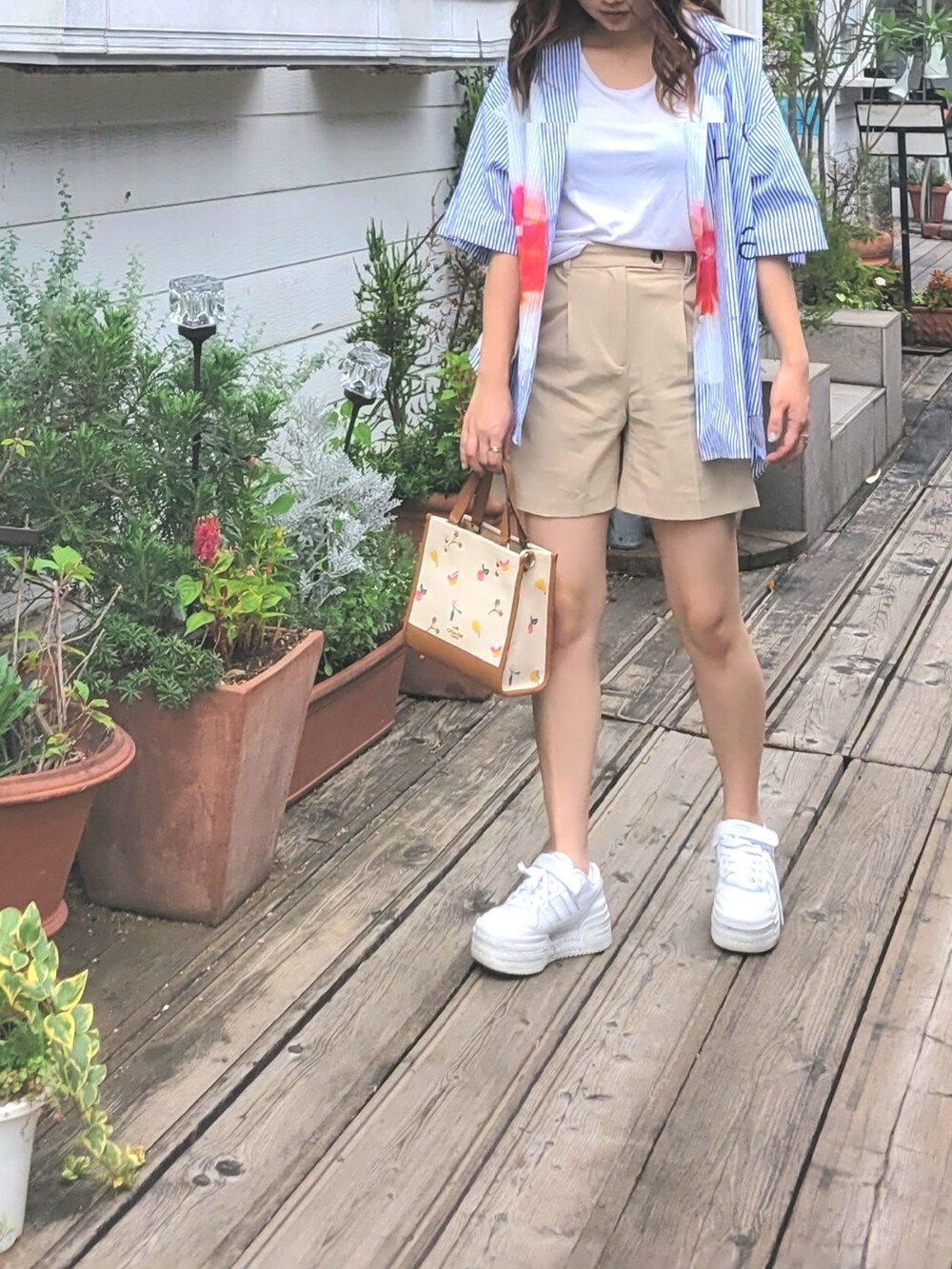 ブルー系のシャツ/ブラウス、ホワイト系のトートバッグ、ホワイト系のスニーカーを着用したレディースの夏コーディネートの2枚目の写真