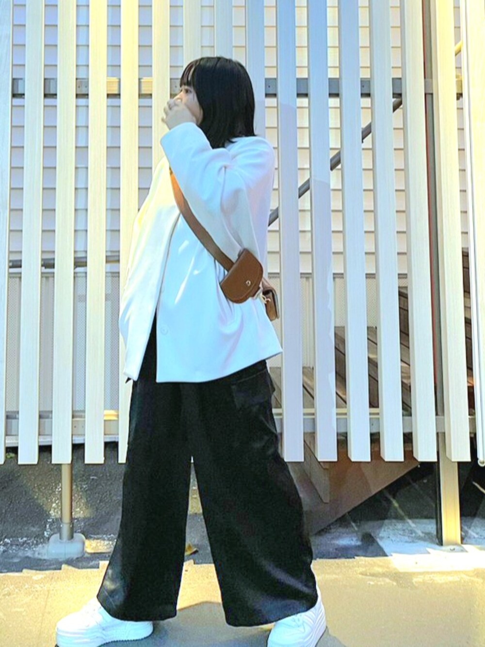 ブラック系のパンツ、ホワイト系のジャケット/アウター、ブラウン系のショルダーバッグを着用したレディースの秋コーディネートの2枚目の写真
