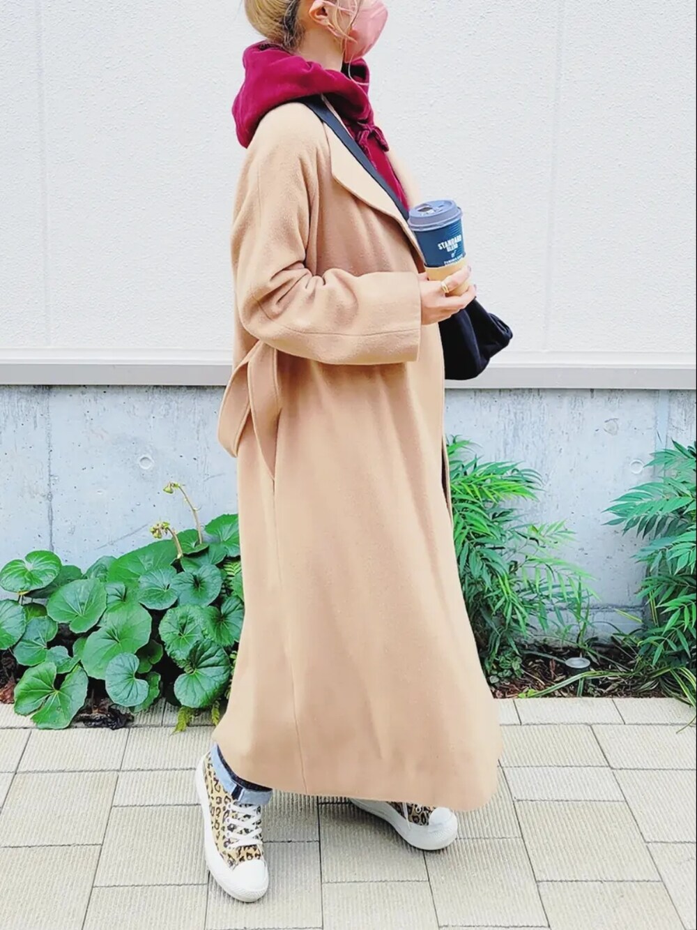 ブルー系のデニムパンツ、ブラック系のショルダーバッグ、ベージュ系のノーカラーコートを着用したレディースの冬コーディネートの2枚目の写真