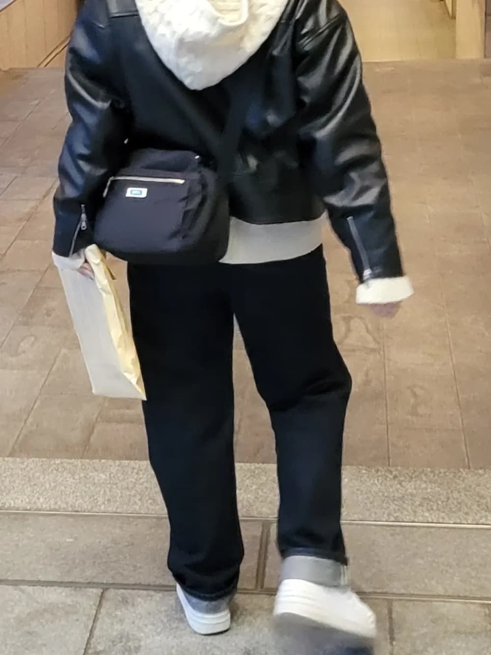 ブルー系のデニムパンツ、ホワイト系のニット/セーター、ブラック系のライダースジャケットを着用したレディースの秋コーディネートの2枚目の写真