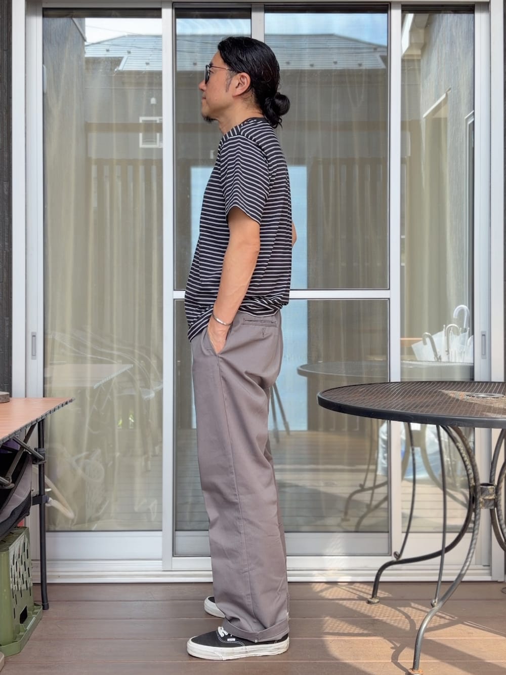 ブラック系のスニーカー、グレー系のチノパンツ、ブラック系のTシャツ/カットソーを着用したメンズの夏コーディネートの2枚目の写真