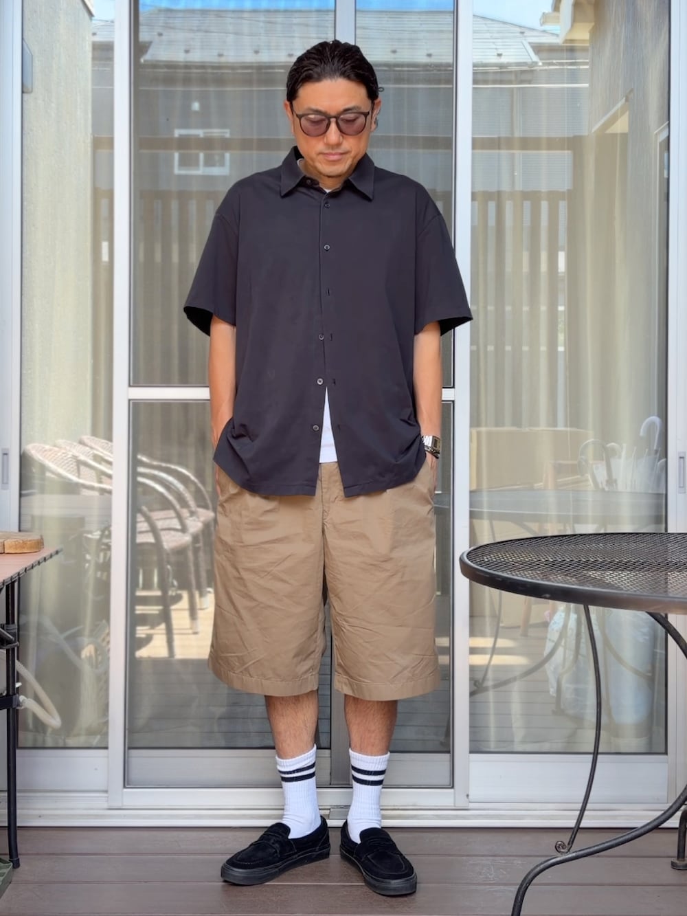 ブラック系のシャツ/ブラウス、ベージュ系のその他パンツ、ブラック系のローファーを着用したメンズの夏コーディネートの2枚目の写真