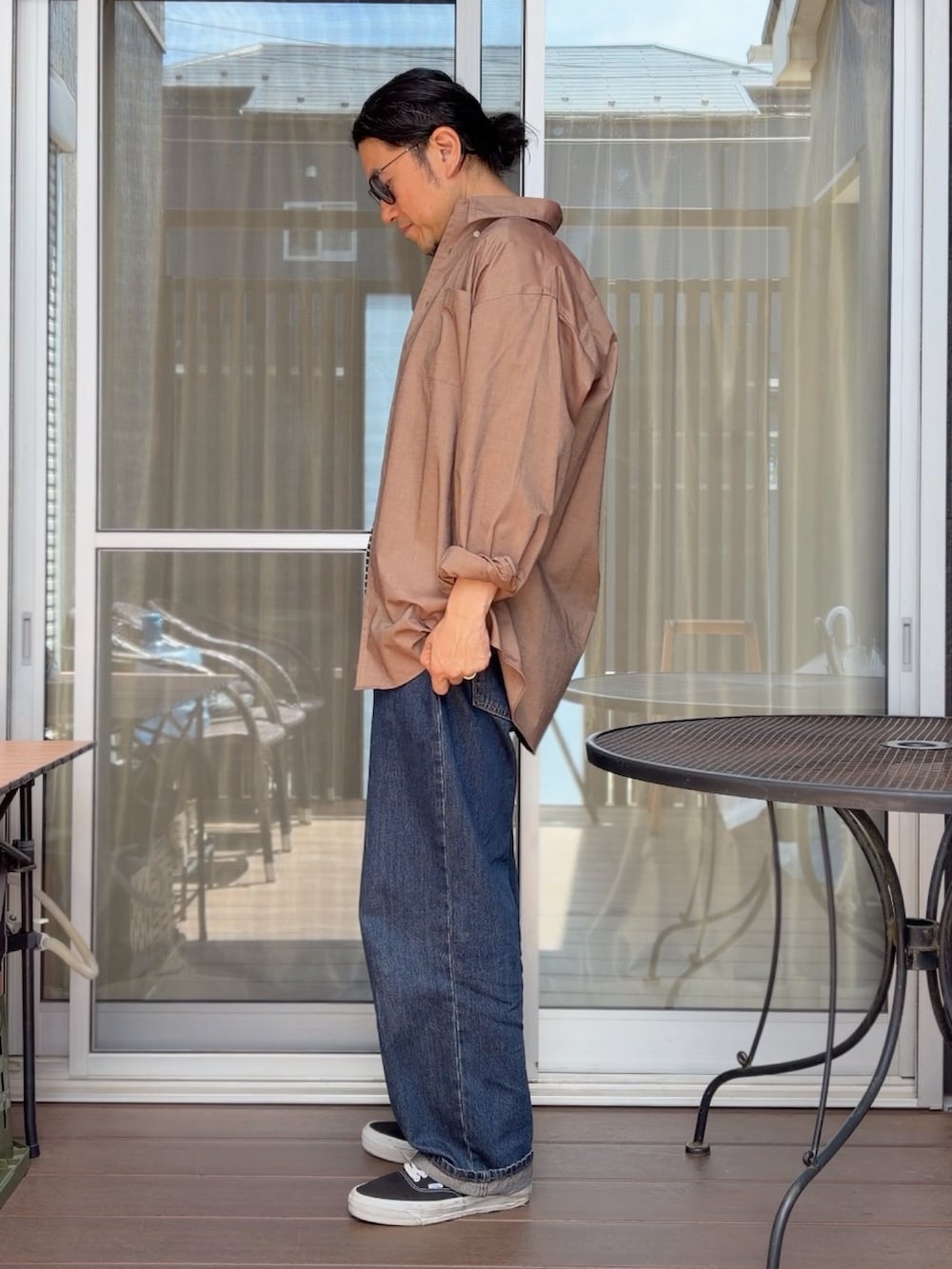 ブルー系のデニムパンツ、ブラック系のスニーカー、ブラック系のTシャツ/カットソーを着用したメンズの春コーディネートの2枚目の写真