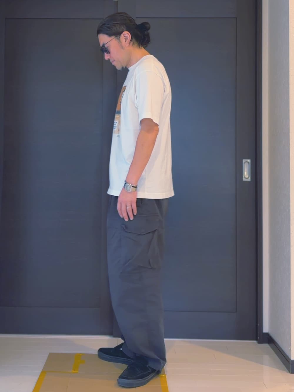 ブラック系のカーゴパンツ、ホワイト系のTシャツ/カットソー、ブラック系のローファーを着用したメンズの夏コーディネートの2枚目の写真