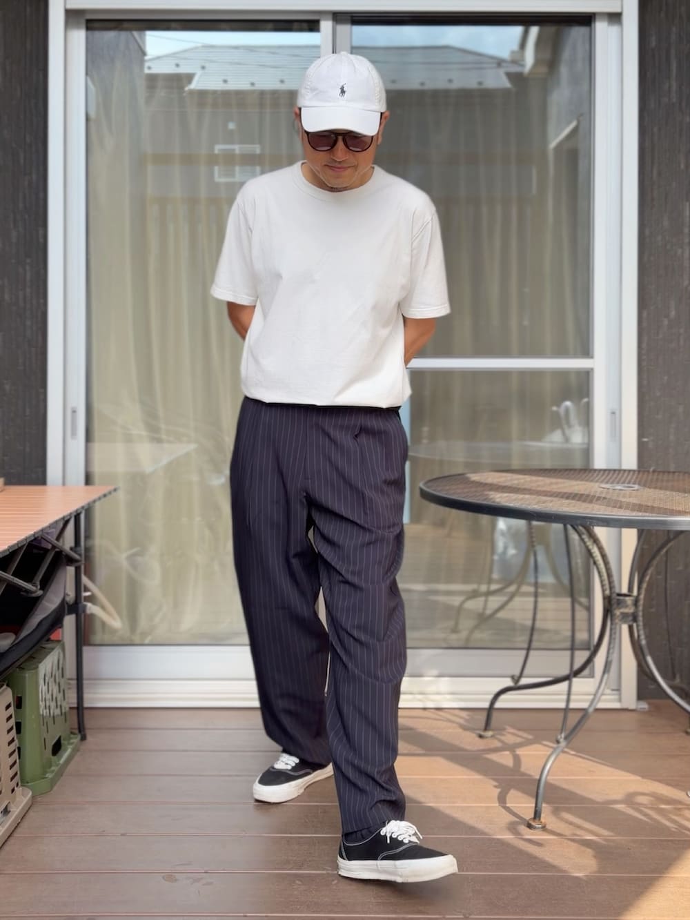 ホワイト系のTシャツ/カットソー、ブルー系のスラックス、ブラック系のスニーカーを着用したメンズの春コーディネートの2枚目の写真