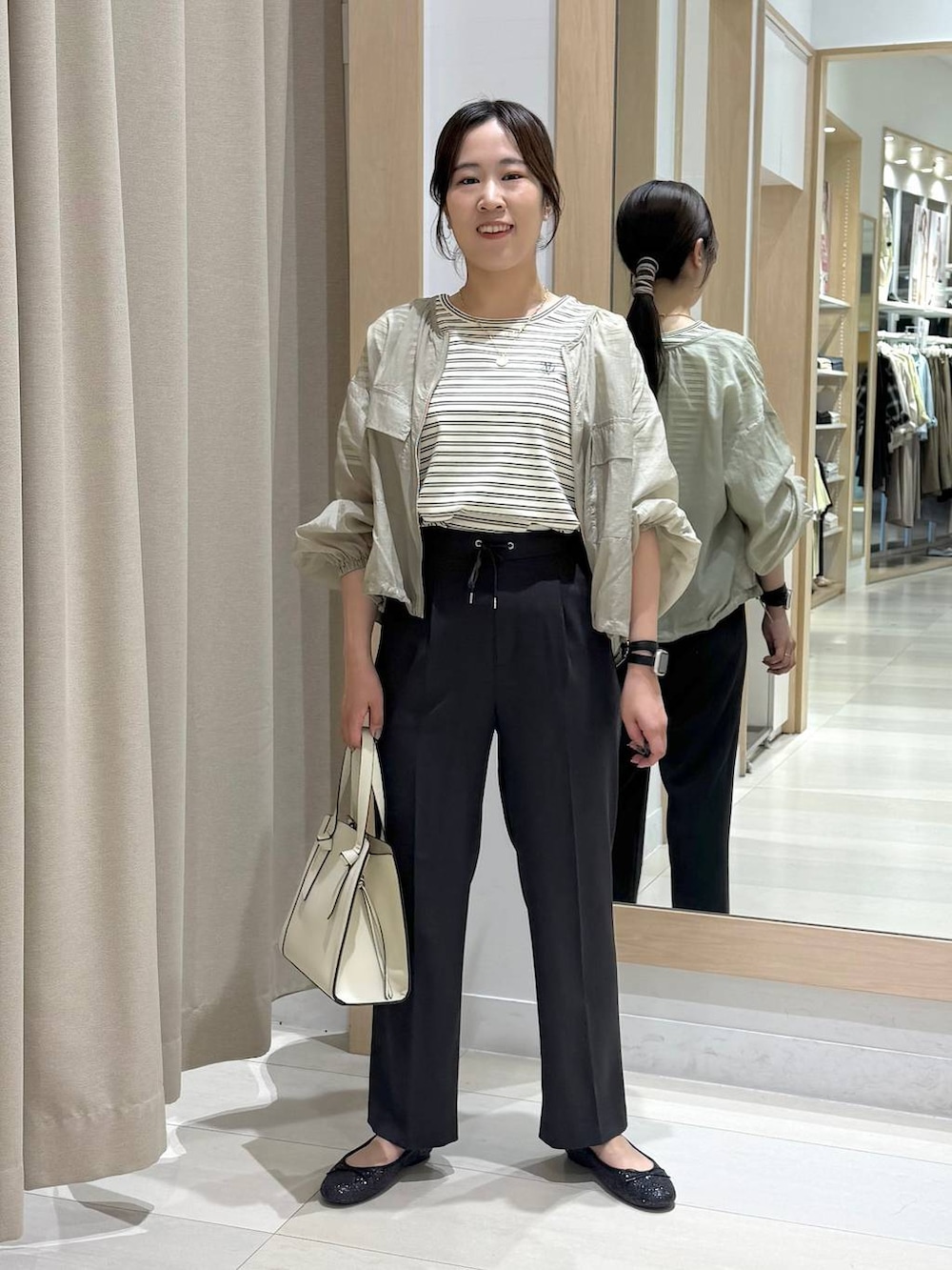 ブラック系のバレエシューズ、ホワイト系のショルダーバッグ、グリーン系のブルゾンを着用したレディースの春コーディネートの6枚目の写真