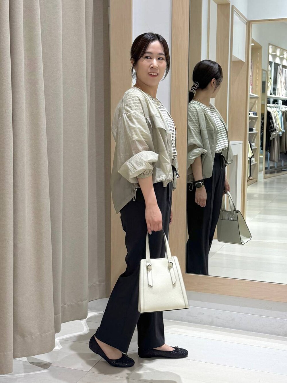 ブラック系のバレエシューズ、ホワイト系のショルダーバッグ、グリーン系のブルゾンを着用したレディースの春コーディネートの3枚目の写真