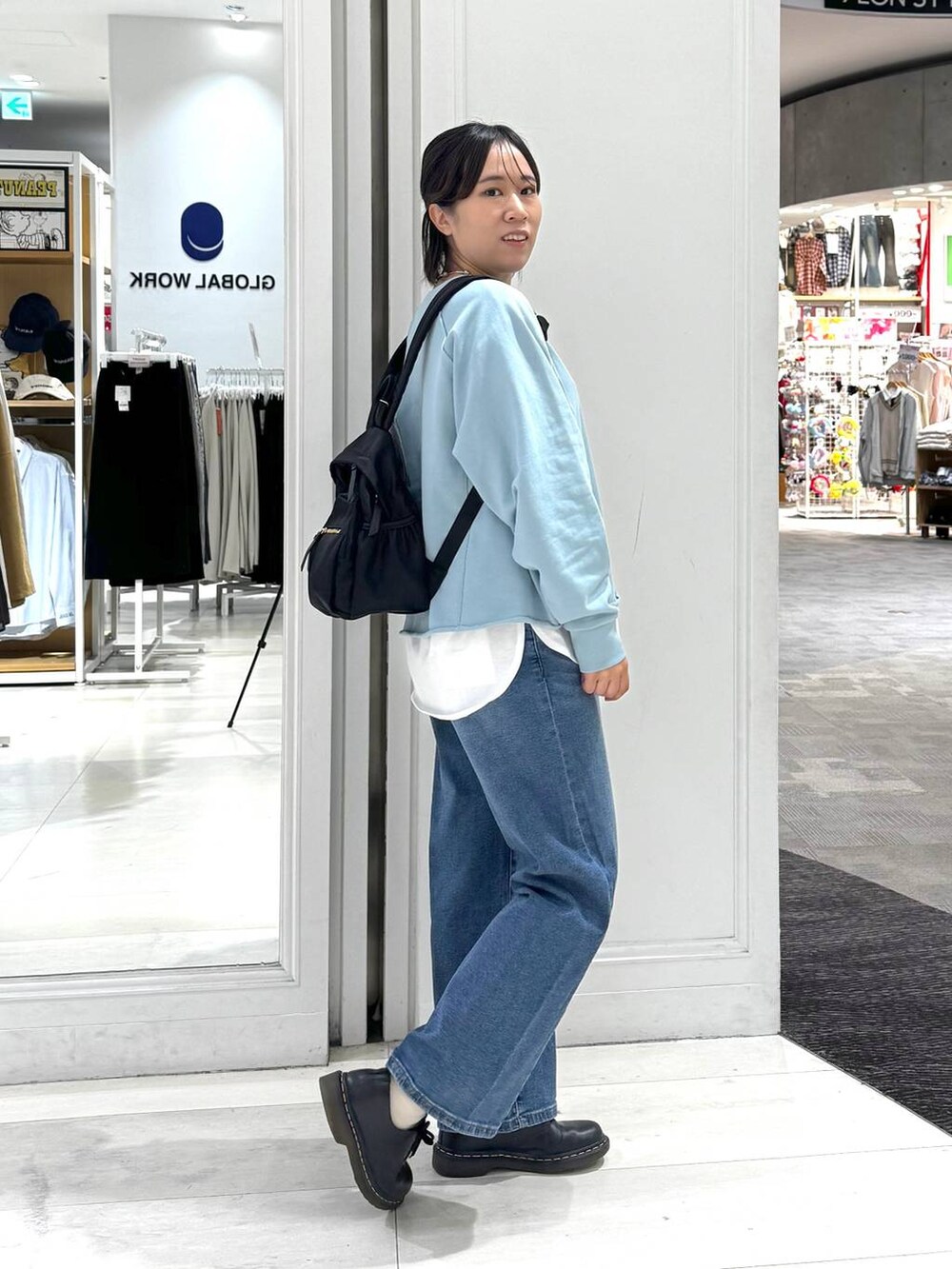 ブラック系のバックパック/リュック、ホワイト系のTシャツ/カットソー、ブルー系のデニムパンツを着用したレディースの秋コーディネートの2枚目の写真