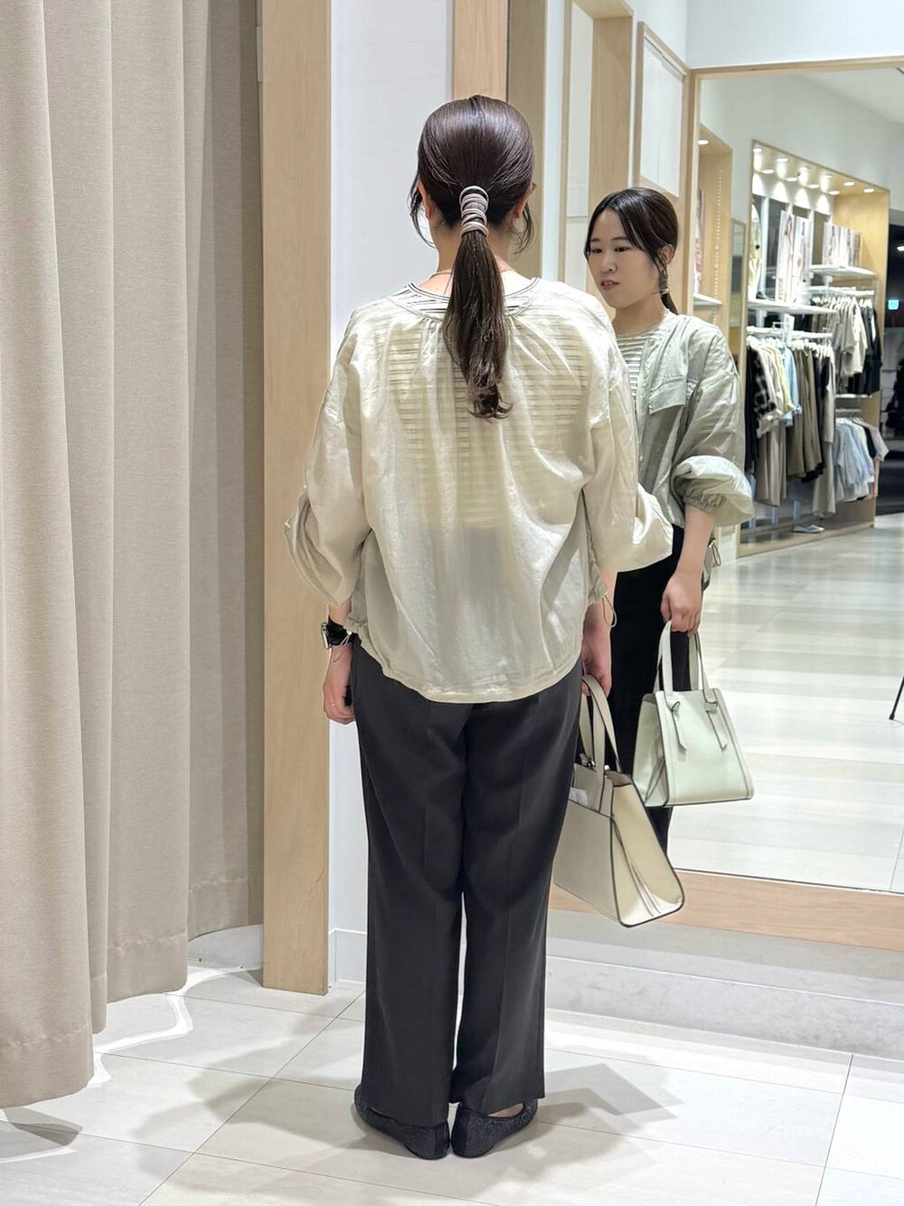 ブラック系のバレエシューズ、ホワイト系のショルダーバッグ、グリーン系のブルゾンを着用したレディースの春コーディネートの4枚目の写真