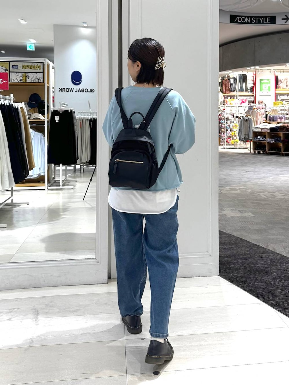 ブラック系のバックパック/リュック、ホワイト系のTシャツ/カットソー、ブルー系のデニムパンツを着用したレディースの秋コーディネートの3枚目の写真