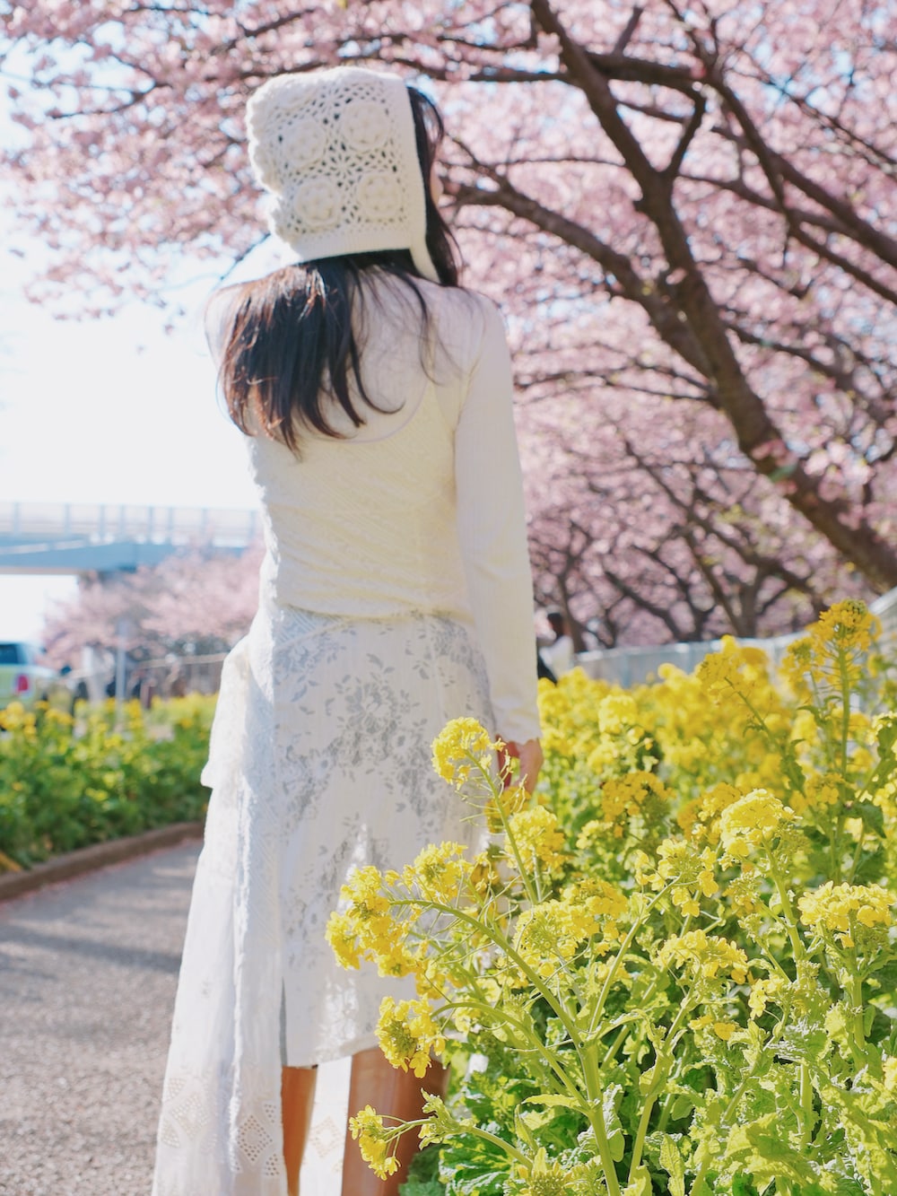 ホワイト系のブルゾン、ホワイト系のジャンパースカート、ホワイト系のTシャツ/カットソーを着用したレディースの冬コーディネートの3枚目の写真