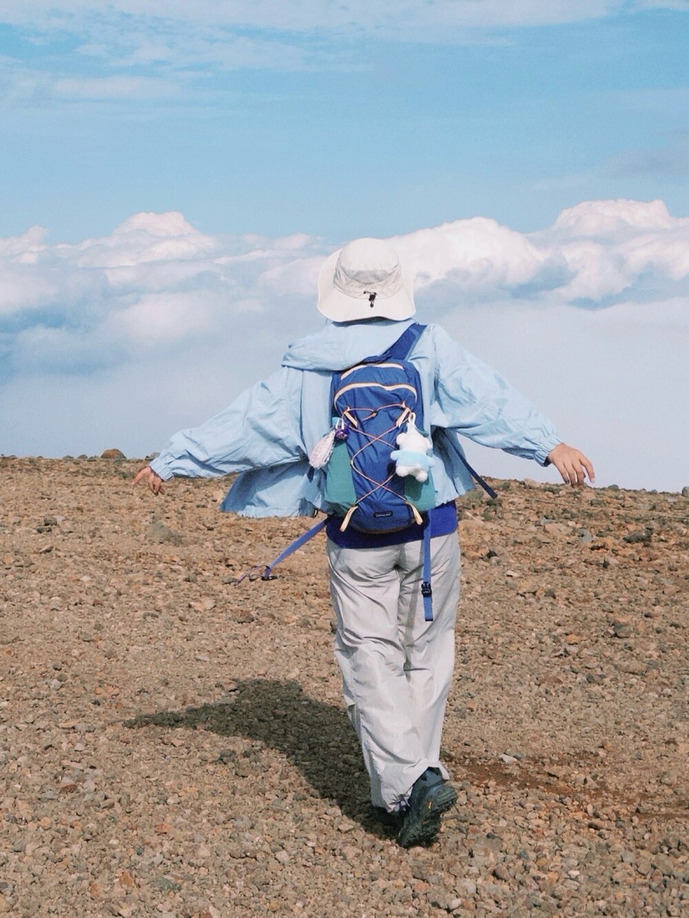 ブルー系のステンカラーコート、パープル系のTシャツ/カットソー、パープル系のバックパック/リュックを着用したレディースの秋コーディネートの2枚目の写真