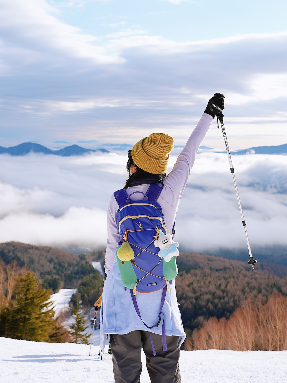 パープル系のTシャツ/カットソー、グレー系のチノパンツ、パープル系のバックパック/リュックを着用したレディースの春コーディネートの3枚目の写真