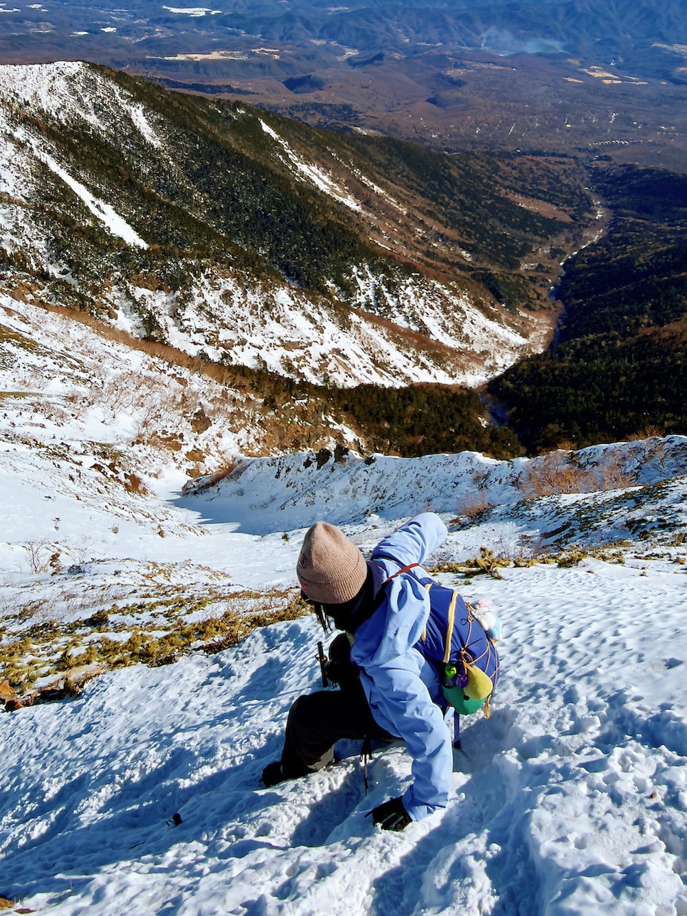 パープル系のマウンテンパーカー、グリーン系のその他シューズ、グレー系のチノパンツを着用したレディースの冬コーディネートの3枚目の写真
