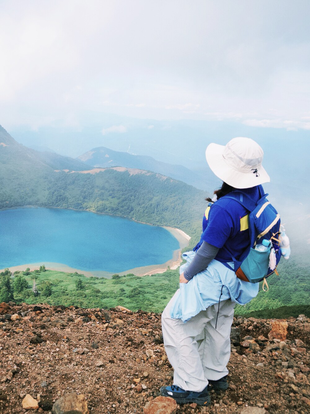 ブルー系のステンカラーコート、パープル系のTシャツ/カットソー、パープル系のバックパック/リュックを着用したレディースの秋コーディネートの3枚目の写真