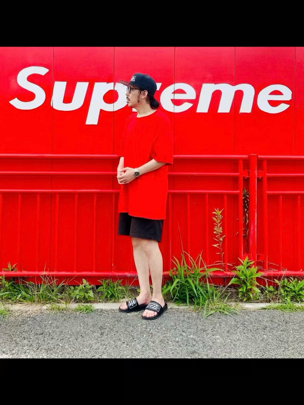 レッド系のTシャツ/カットソー、ブラック系のサンダル、ブラック系のキャップを着用したメンズの春コーディネートの3枚目の写真