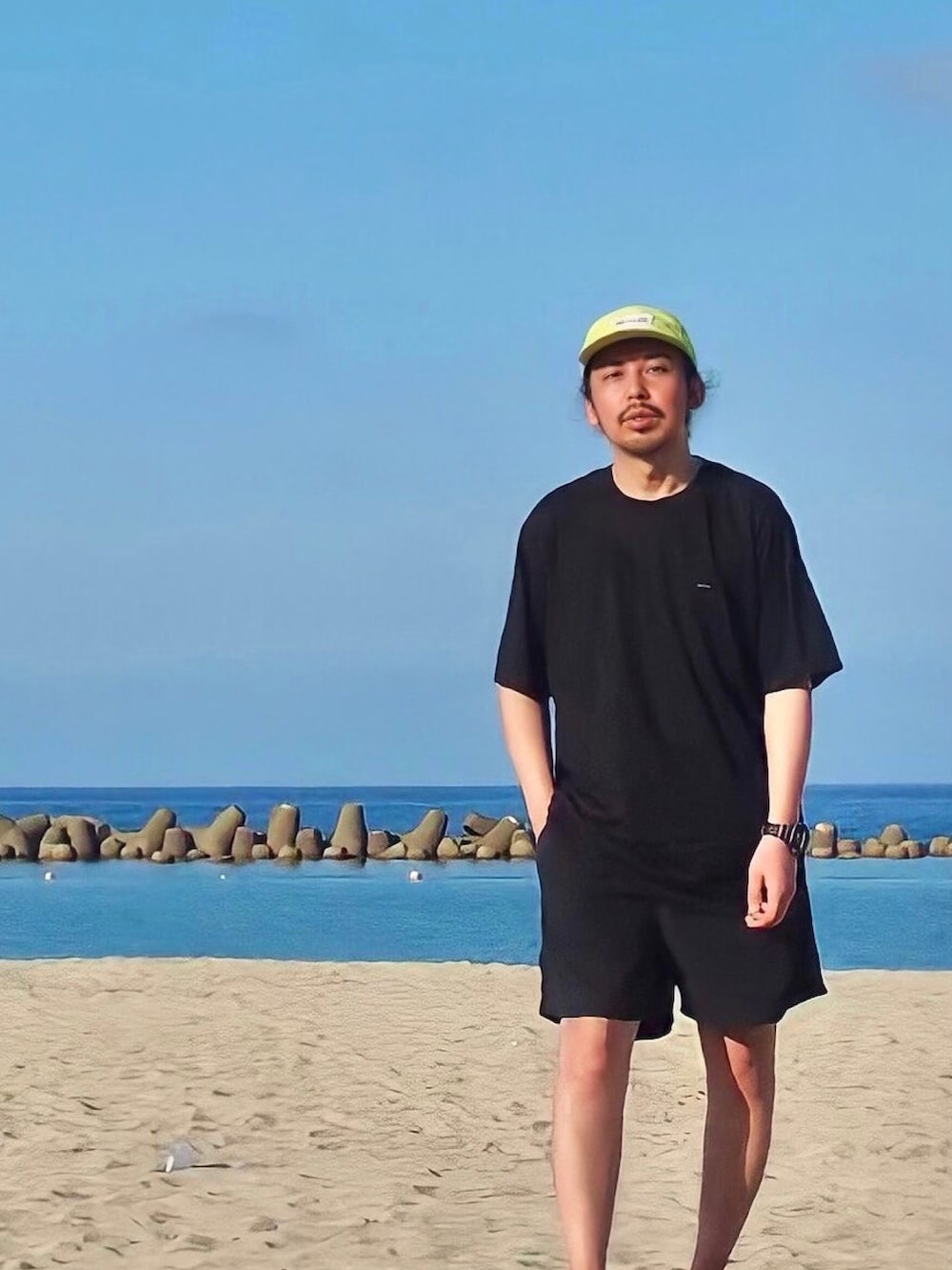 ブラック系のTシャツ/カットソー、ブラック系のスニーカー、グリーン系のキャップを着用したメンズの春コーディネートの2枚目の写真