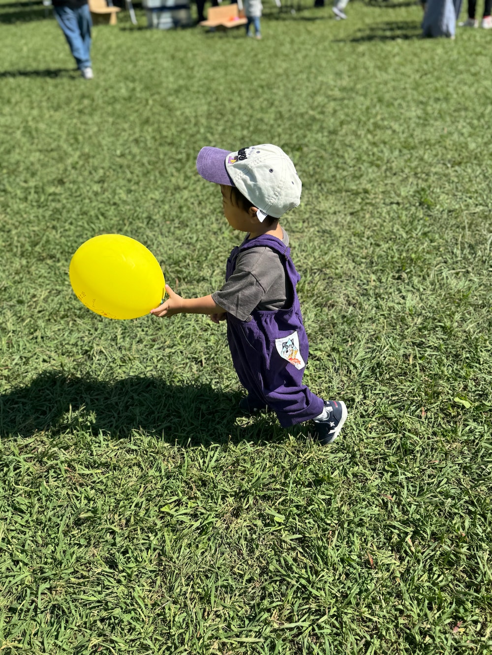 パープル系のサロペット/オーバーオール、ホワイト系のスニーカー、ベージュ系の帽子を着用したキッズの秋コーディネートの2枚目の写真