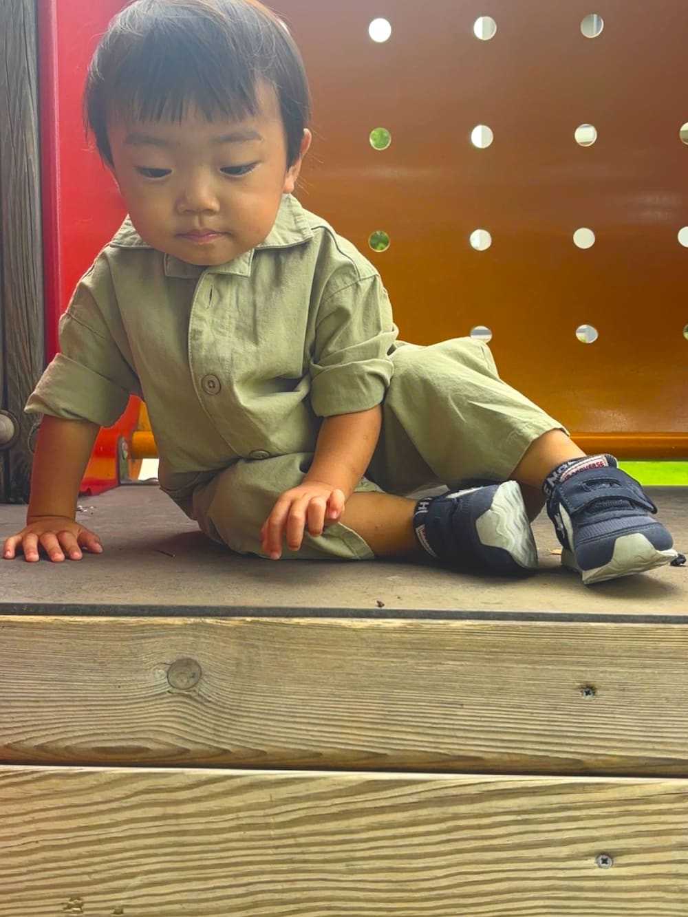 グリーン系のオールインワン・サロペット、ホワイト系のスニーカー、ブラック系のキャップを着用したキッズの秋コーディネートの2枚目の写真