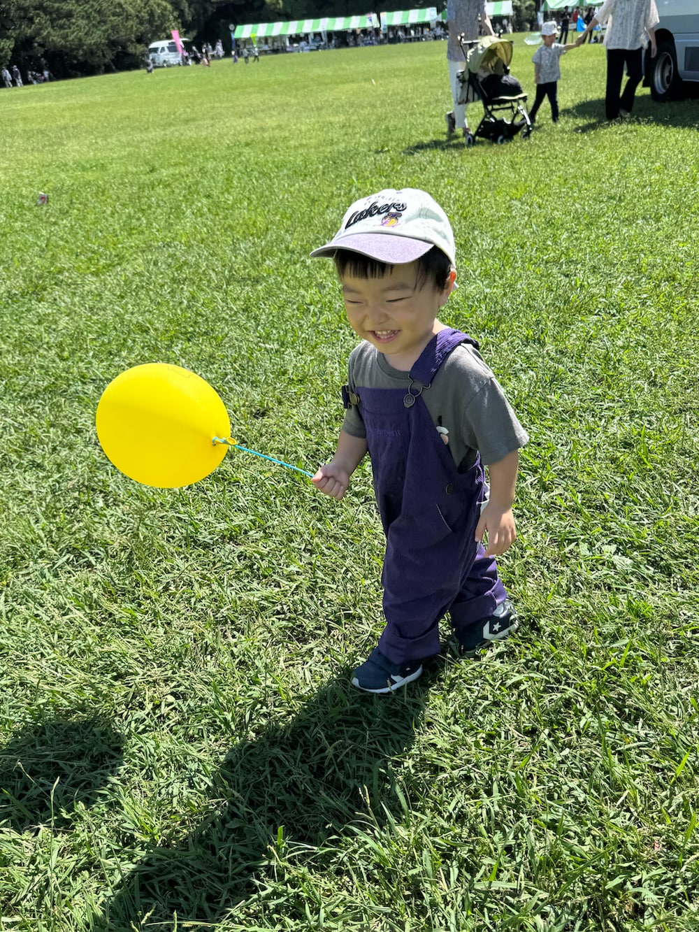 パープル系のサロペット/オーバーオール、ホワイト系のスニーカー、ベージュ系の帽子を着用したキッズの秋コーディネートの3枚目の写真