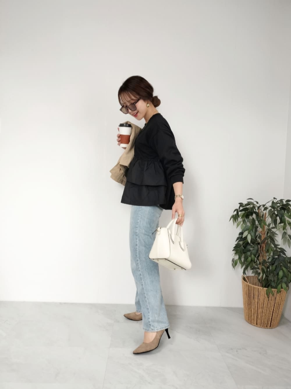 ブラック系のトップス、ベージュ系のパンプス、ホワイト系のショルダーバッグを着用したレディースの冬コーディネートの2枚目の写真