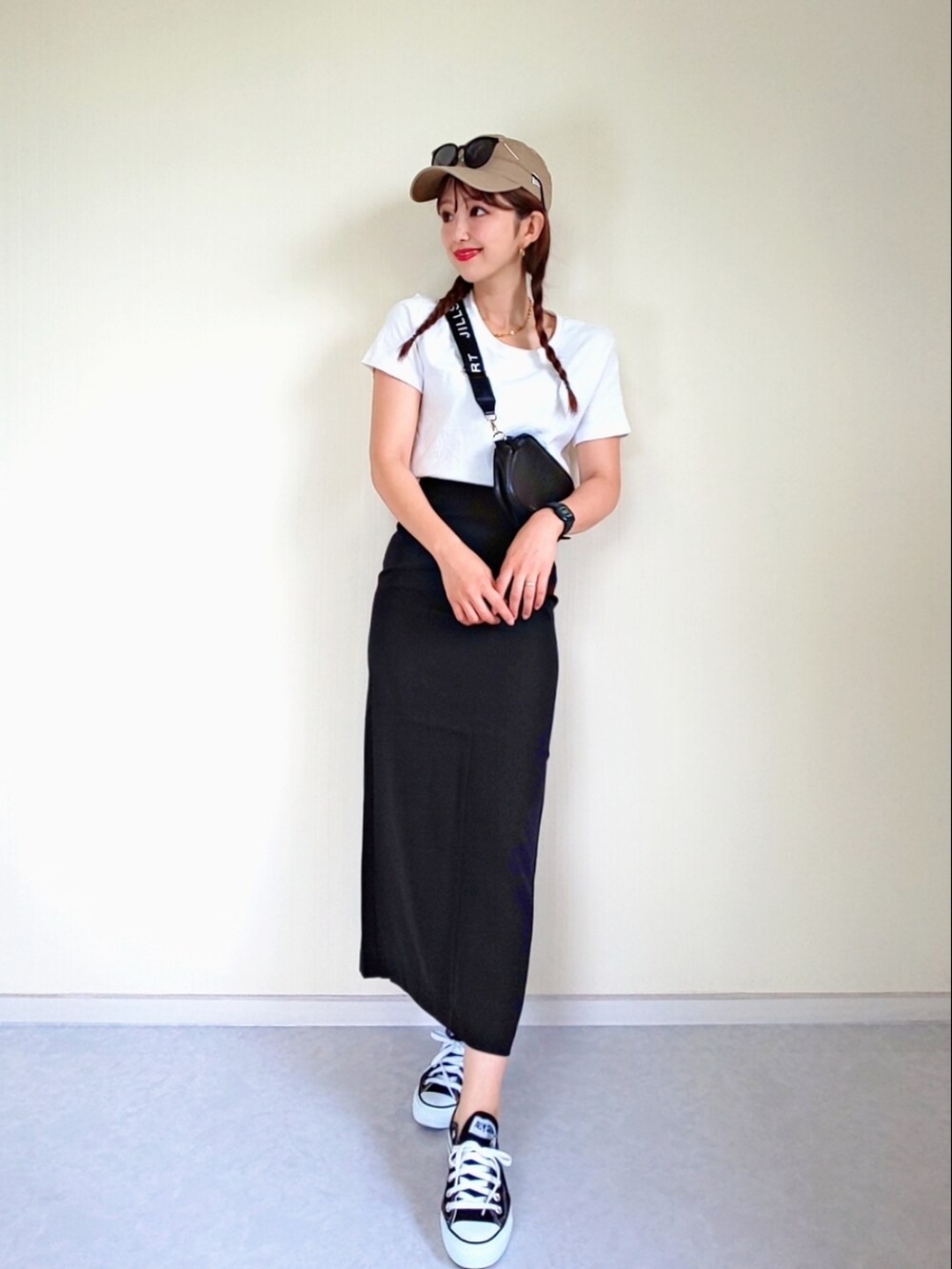 ブラック系のスカート、ホワイト系のTシャツ/カットソー、ブラック系のスニーカーを着用したレディースの夏コーディネートの2枚目の写真