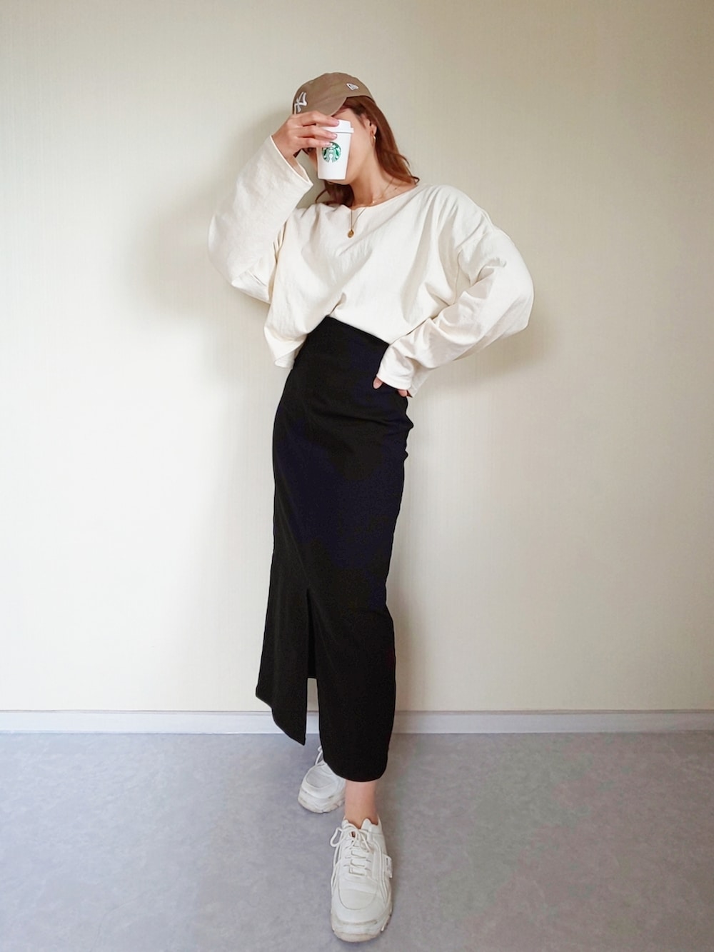 ブラック系のスカート、ベージュ系のキャップを着用したレディースの春コーディネートの2枚目の写真