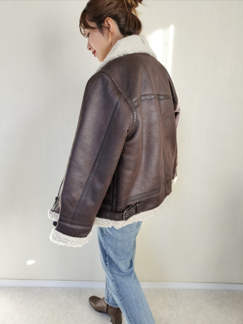 ホワイト系のニット/セーター、ブラウン系のムートンコートを着用したレディースの秋コーディネートの3枚目の写真