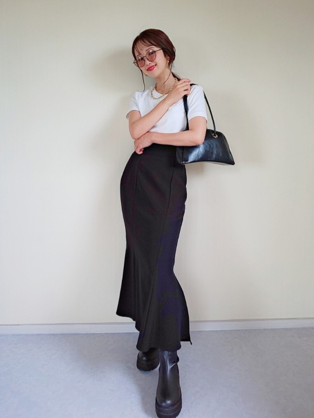 ブラック系のハンドバッグ、ブラック系のスカート、ブラック系のブーツを着用したレディースの夏コーディネートの2枚目の写真
