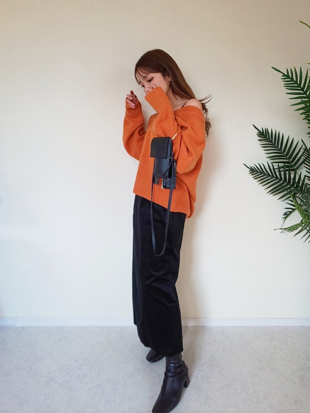 オレンジ系のニット/セーター、ブラック系のワンピース、ブラック系のショルダーバッグを着用したレディースの冬コーディネートの3枚目の写真