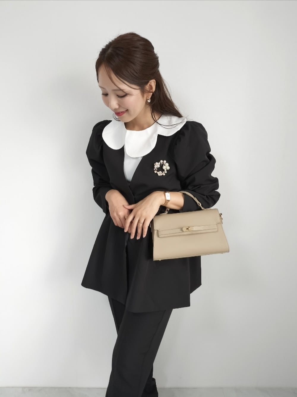 ブラック系のスーツセットを着用したレディースの秋コーディネートの2枚目の写真