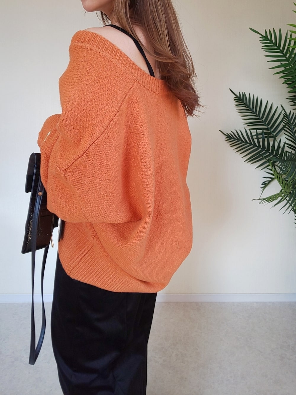 オレンジ系のニット/セーター、ブラック系のワンピース、ブラック系のショルダーバッグを着用したレディースの冬コーディネートの2枚目の写真