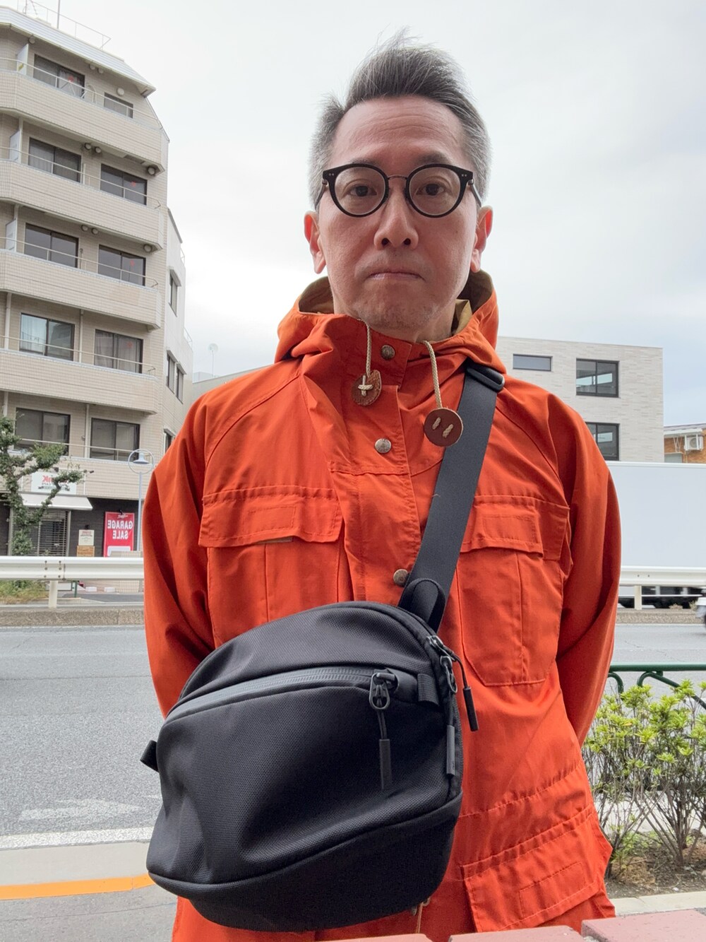 ブラック系のその他パンツ、ブラック系のスニーカー、オレンジ系のマウンテンパーカーを着用したメンズの秋コーディネートの2枚目の写真
