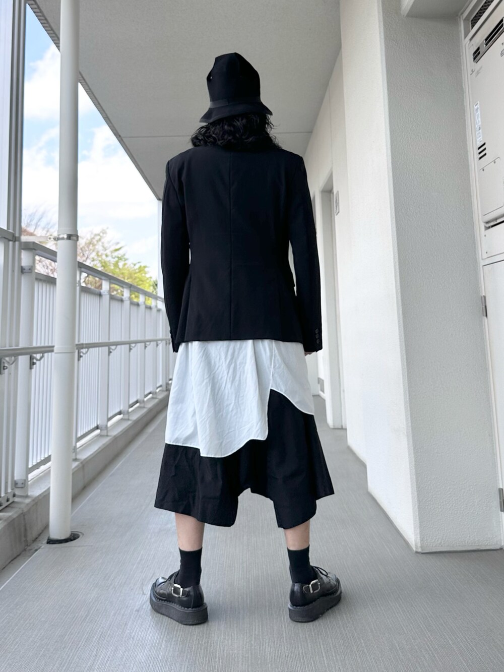 ブラック系のテーラードジャケット、ホワイト系のトップス、ブラック系のパンツを着用したメンズの春コーディネートの3枚目の写真