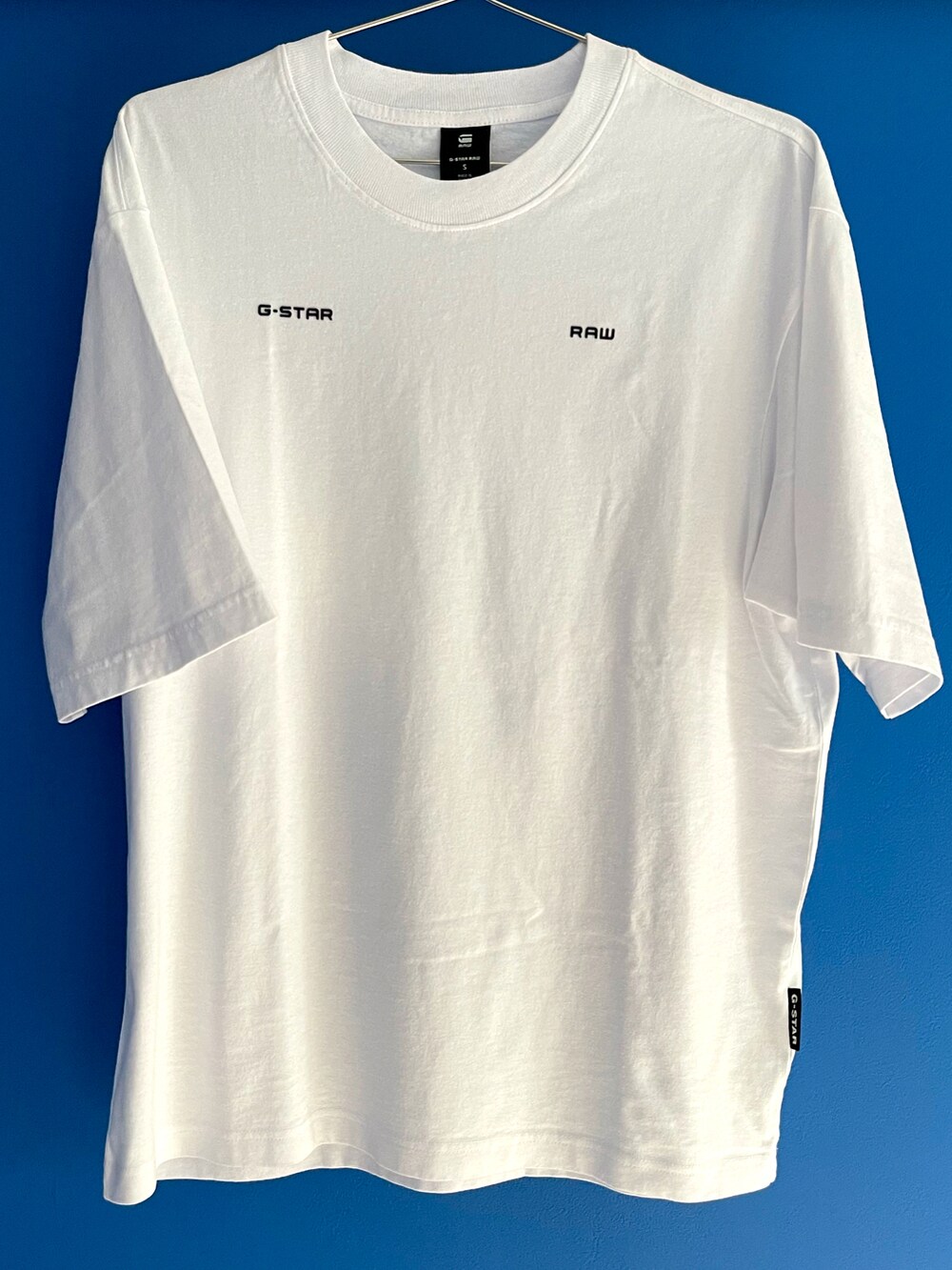 ホワイト系のTシャツ/カットソー、ブラック系のデニムパンツ、ブラック系のスニーカーを着用したメンズの夏コーディネートの2枚目の写真