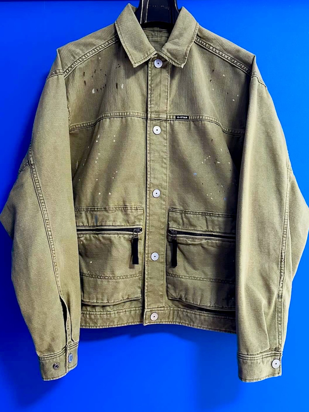 グリーン系のブルゾン、ブラック系のデニムパンツ、ホワイト系のスニーカーを着用したメンズの春コーディネートの2枚目の写真