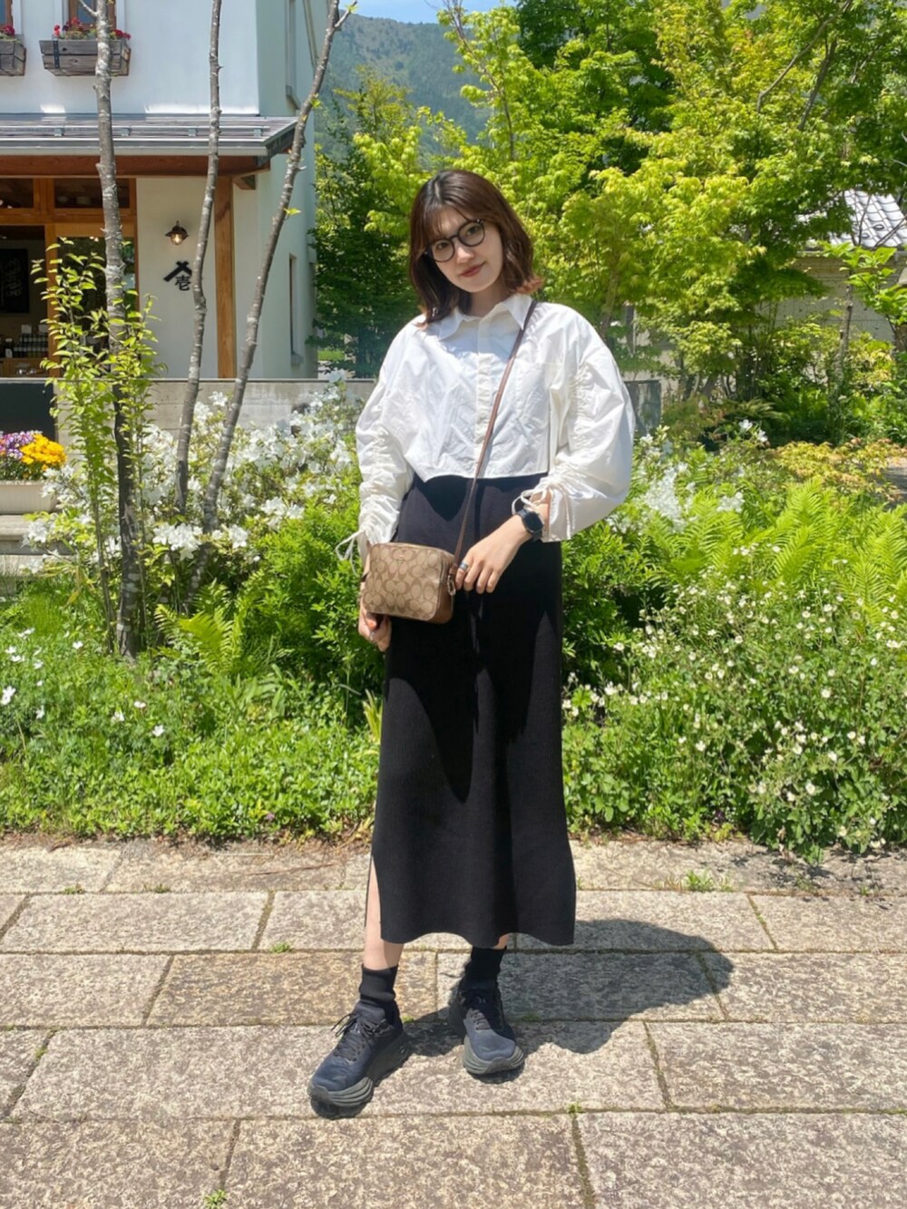 イエロー系のシャツ/ブラウス、ブラック系のワンピース、ホワイト系のハンドバッグを着用したレディースの春コーディネートの2枚目の写真